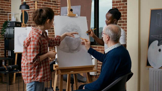 Teacher And Student Helping Old Man To Draw Vase On Canvas, Explaining Drawing Skills. Senior Person Attending Art Class Lesson As New Years Resolutions To Develop Educational Growth.