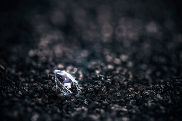 Diamond still life - A single solitaire Diamond in amongst some pieces of black coal background