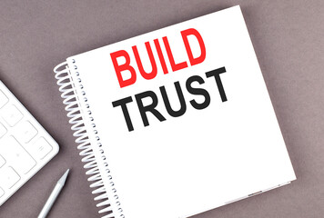 BUILD TRUST text on notebook with calculator and pen,business concept