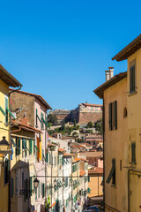 Fototapeta na wymiar Street with typical Italian houses in the island capital Portoferraio on the island of Elba in Italy under a bright blue sky in summer