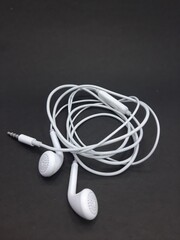 Rolled white earphone on black background.