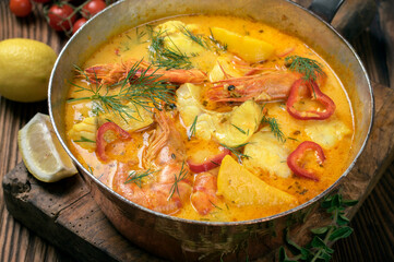 Traditional Brazilian fish soup moqueca de peixe with seafood and potatoes served as close-up in a rustic casserolle