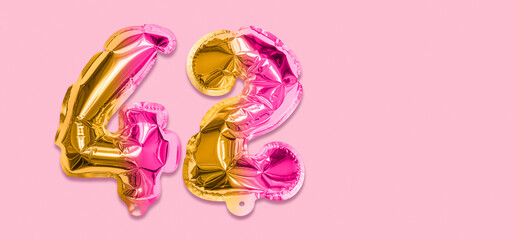 Rainbow foil balloon number, digit forty two on a pink background. Birthday greeting card with...