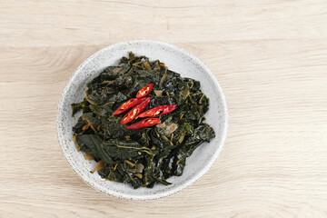 Stir Fry Papaya Leaves or Tumis Daun Pepaya, a traditional Indonesian dish made from boiled papaya leaves stir-fried with spices and chilies.
