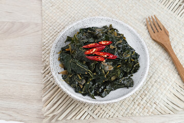 Stir Fry Papaya Leaves or Tumis Daun Pepaya, a traditional Indonesian dish made from boiled papaya leaves stir-fried with spices and chilies.
