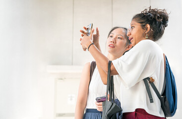 Two young women with different ethnicity looking at a smartphone together. Copy space.