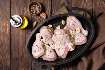Raw chicken meat. Uncooked chicken legs on wooden cooking table background with spices. View from above.