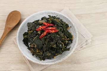 Stir Fry Papaya Leaves or Tumis Daun Pepaya, a traditional Indonesian dish made from boiled papaya leaves stir-fried with spices and chilies.
