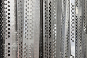 Plastering rebars - perforated metal stripes. Industrial vertical background texture
