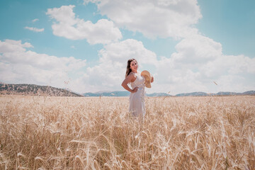 a woman in a white dress among the wheat ears at sunset