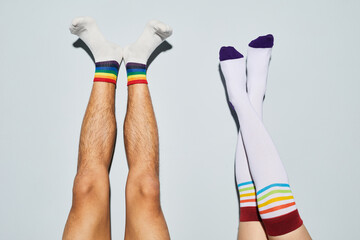 Minimal shot of playful young couple wearing socks with rainbow symbols feet up against white wall