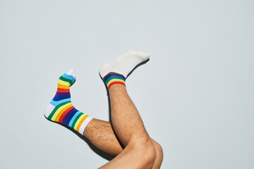 Minimal shot of playful man wearing mismatched socks with rainbow symbols feet up, copy space