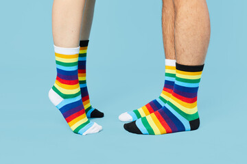 Minimal shot of couple wearing rainbow socks kiss on pastel blue background