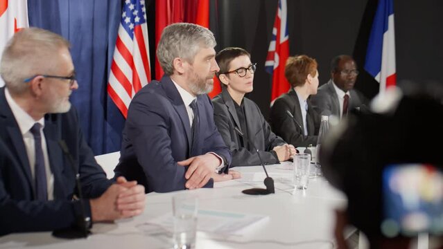 Group of multiethnic male and female political leaders having discussion while participating in international press conference
