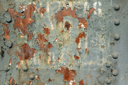 Peeling paint rust texture grunge background of a grey white painted vintage cast iron textured panel frame with metal rivets, stock photo image