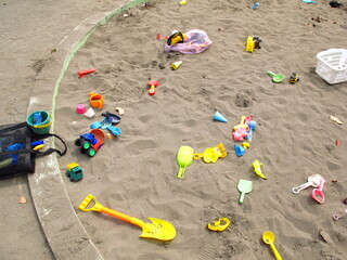 幼子の砂遊びに飽きた後の玩具の残る春の砂場風景 - obrazy, fototapety, plakaty