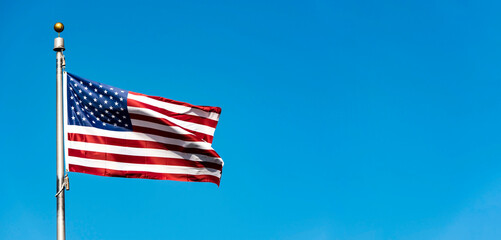 Flag of the USA against blue sky, long panoramic picture with space for text