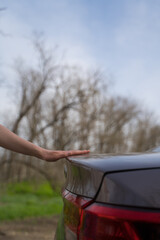 A woman closes the trunk of a gray modern car