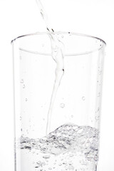 Pouring water into glass on white background. Stream of water into a glass beaker. Shallow depth of field