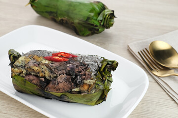 Nasi Bakar Calamari, rice wrapped in banana leaves with stir-fried black squid and egg then grilled. Selected focus.
