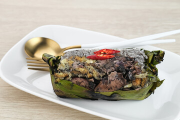 Nasi Bakar Calamari, rice wrapped in banana leaves with stir-fried black squid and egg then grilled. Selected focus.
