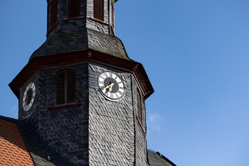 Church clock. Close up church tower with roff shingles. Ancient clock and old white, black and...