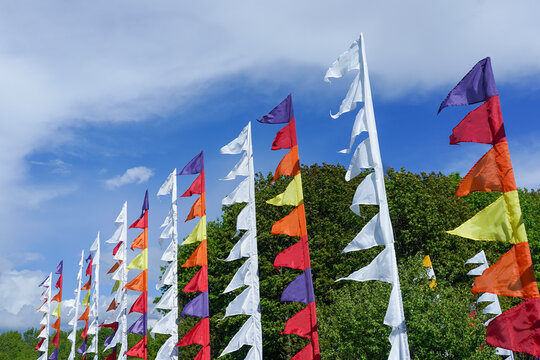 Colorful triangular flags waved in the wind with blue sky and trees in the background