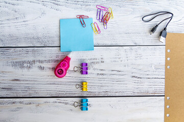 Blue sheets for notes, colored paper clips, a sheet of craft paper, paper clips, a charger for...