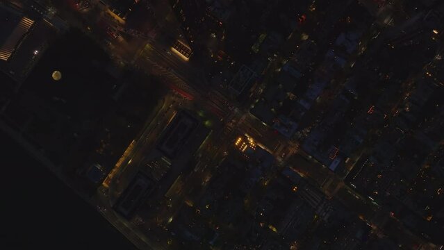 Aerial birds eye overhead top down panning view of night city. Cars driving in streets between high rise buildings. Manhattan, New York City, USA