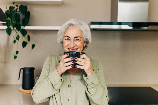 Happy senior woman enjoying a cup of tea at home