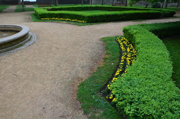Obraz premium stone sandstone circular fountain in the park. built of sandstone filled with water. lined with a light threshing gravel road with a border of granite cubes, flowerbeds with orange flowers