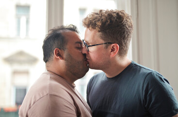 homosexual couple is kissing at home