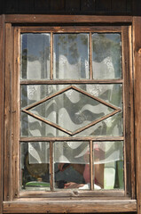 a small rustic window with a curtain photographed from the outside. carved Russian window of the hut