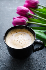 Cup of coffee with bouquet of pink tulips