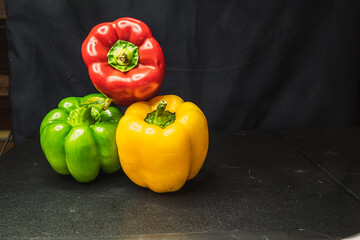 Orange yellow red bell peppers green peppers  on dark background 