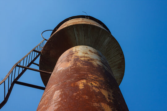Old rusty water tower on blue sky background