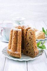 Traditional American bundt cake with icing sugar topping and raisins served as close-up on a design plate