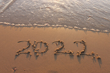 The word summer 2022 written in sea sand. Warm sunset time, vacation and enjoyment
