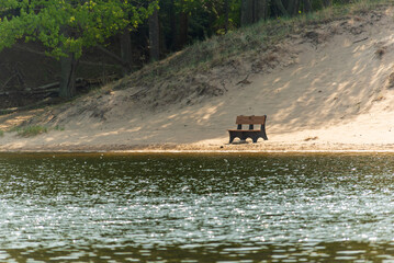 Obraz na płótnie Canvas Front view of a solitude bench over looking water on a sandy beach