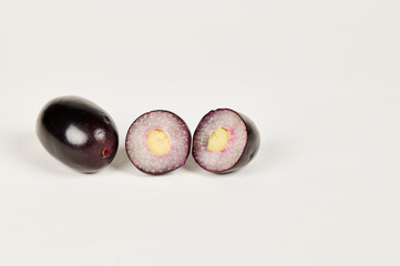 Whole and cut Jambolan plum or Java Plum or Jamun fruit on a white background