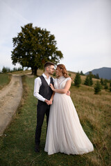 happy stylish bride and groom running and having fun in mountains on summer sunny day