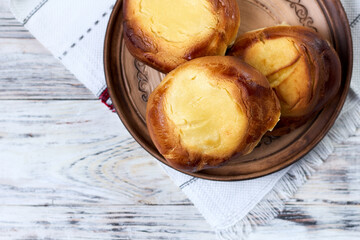 Top view of cheesecake with cottage cheese in a clay plate on white wooden background