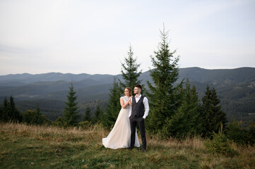 happy stylish bride and groom running and having fun in mountains on summer sunny day