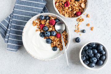 Yogurt granola bowl with blueberries on grey concrete background. Top view. Healthy breakfast or snack food