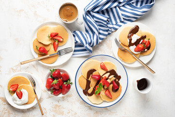 Family breakfast pancakes with strawberries and cream and chocolate sauce, top view flat lay composition