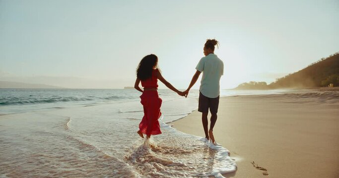 Amazing tropical beach vacation, young black couple walking on the beach at sunset