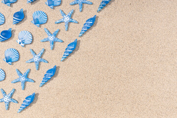Fototapeta na wymiar Summer background with blue seashell pattern on beach sand background. Copy space. Top view
