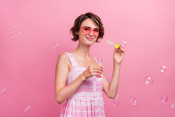 Photo of young attractive girl have fun air fly soap bubbles wear sarafan isolated over pink color...