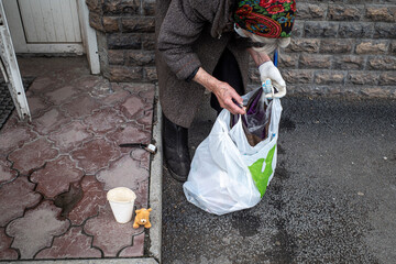 An elderly woman puts spilled things in a bag on the porch of the store