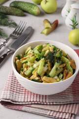 Healthy salad with rhubarb, cucumber, apple and green onion dressed with olive oil in a white bowl on light gray background